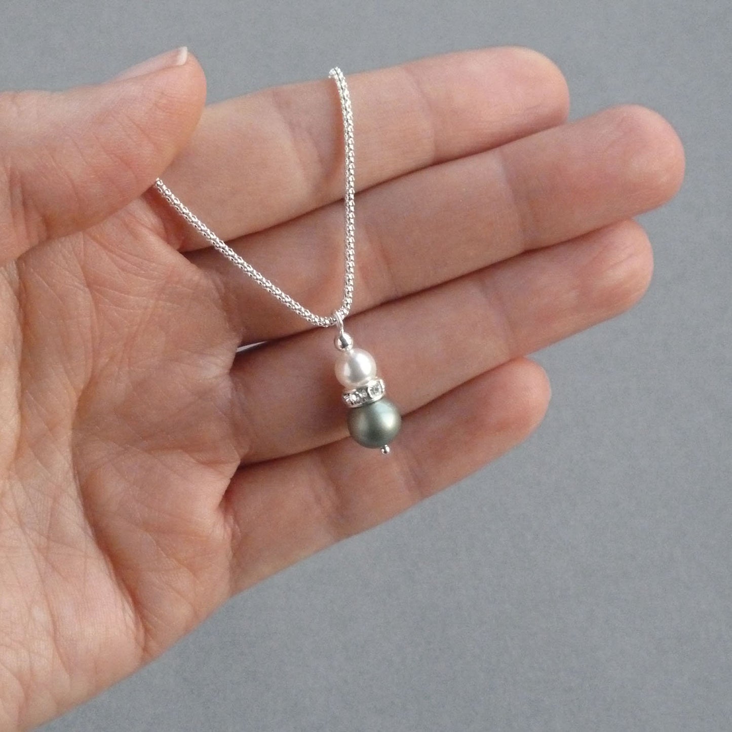 Dainty pendant necklace made with sage green and white pearls and a crystallised band around the centre.